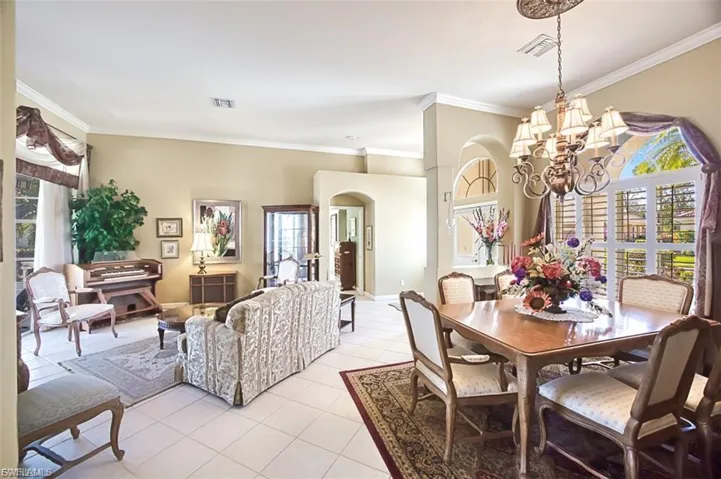 Dining area with arched walkways, crown molding, light tile patterned flooring, and a chandelier