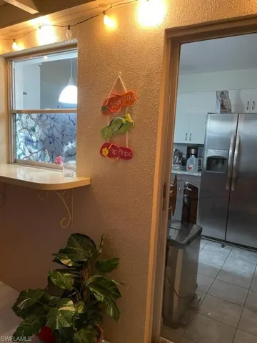 Room details with light tile patterned floors and stainless steel refrigerator with ice dispenser