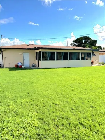 Back of house featuring a yard and a sunroom