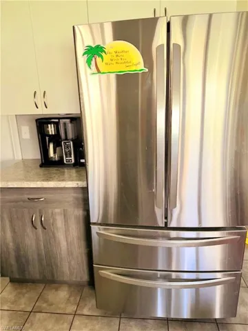 Room details with light tile patterned flooring, white cabinets, and stainless steel fridge
