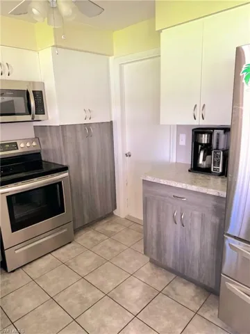 Kitchen with white cabinets, ceiling fan, and stainless steel appliances