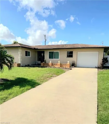 Ranch-style house featuring a garage and a front yard