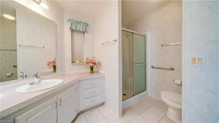 This oversize master bath enjoys a shower with glass shower door, elevated toilet, large vanity, and tile patterned floors.