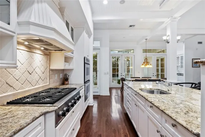 Kitchen featuring a sink, french doors, stainless steel appliances, beamed ceiling, and custom exhaust hood