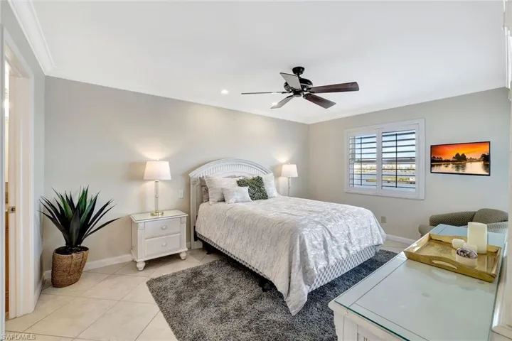Tiled bedroom featuring molding and ceiling fan