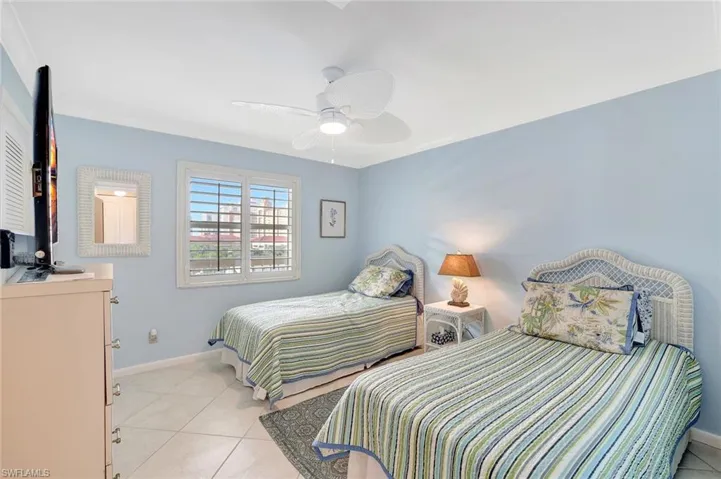 Bedroom with ceiling fan, ornamental molding, and light tile patterned floors