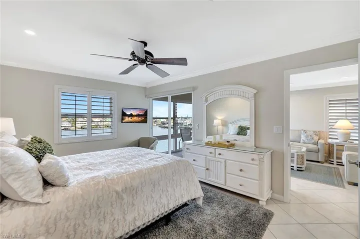 Tiled bedroom featuring ceiling fan, a water view, crown molding, and access to exterior