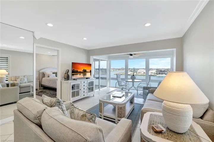 Living room with ceiling fan, light tile patterned floors, and crown molding