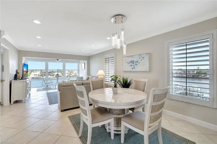 Tiled dining room with ornamental molding, a water view, and an inviting chandelier