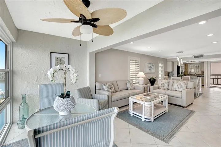 Tiled living room featuring ceiling fan and crown molding