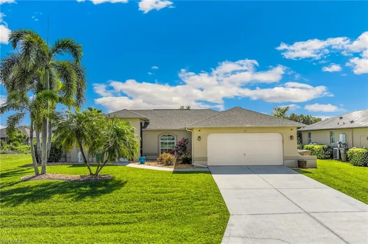 The property features a well-maintained front yard with a lush green lawn and mature palm trees