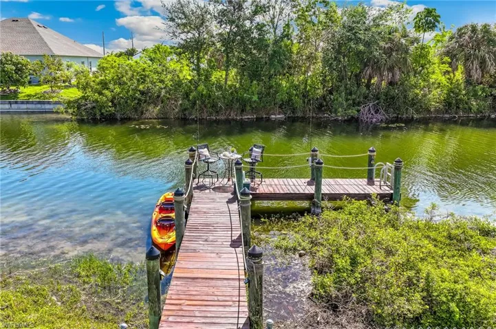 Private wooden dock extending into the waterway, featuring a seating area and lush natural surroundings.