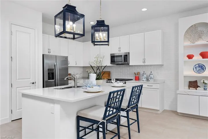 Kitchen featuring white cabinetry, stainless steel appliances, light countertops, and a sink