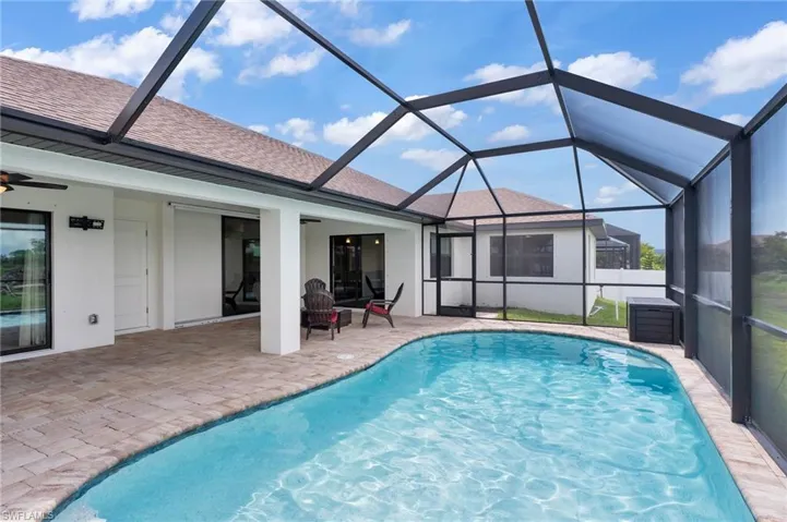 Outdoor pool featuring a sunroom, glass enclosure, and a patio area