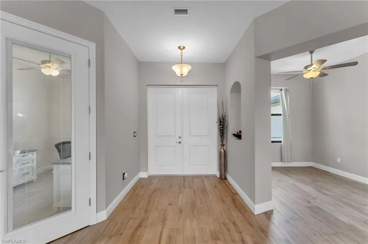 Foyer with a ceiling fan, light wood-type flooring, and arched walkways