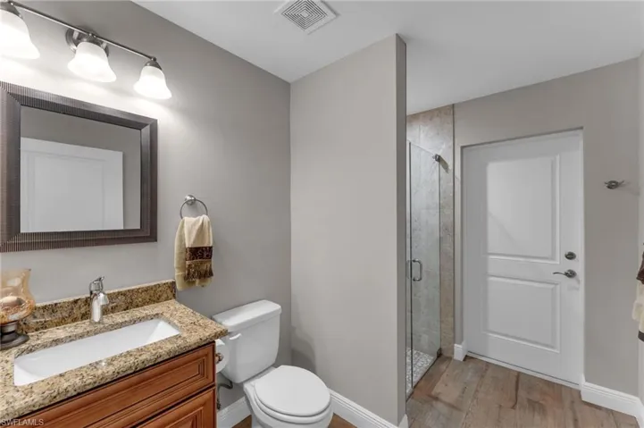 Full bathroom featuring a stall shower, vanity, and light wood finished floors
