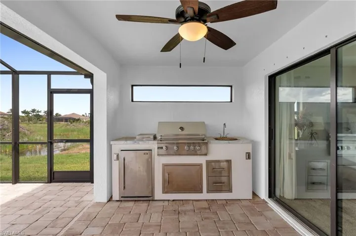 View of patio / terrace with an outdoor kitchen, a sunroom, a lanai, a water view, and a ceiling fan