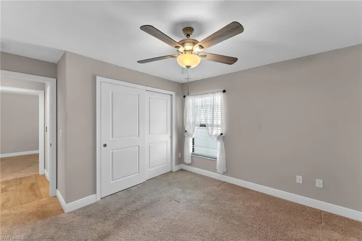 Unfurnished bedroom featuring light carpet, a closet, and ceiling fan