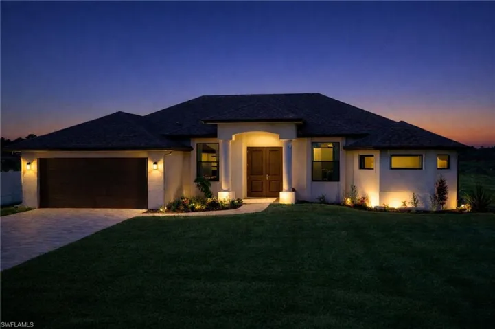 Prairie-style house featuring a front lawn, stucco siding, driveway, and a garage