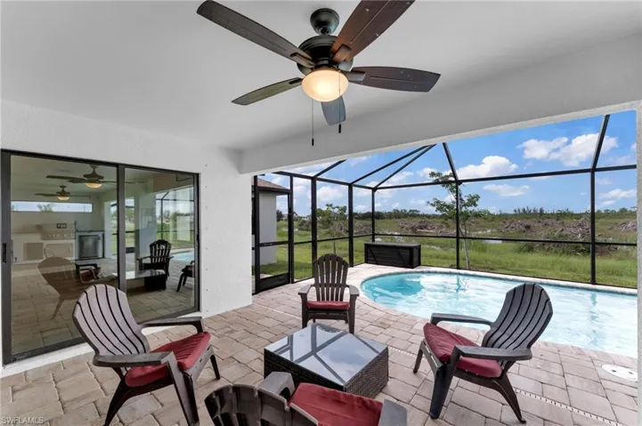 View of patio / terrace featuring a ceiling fan, a sunroom, glass enclosure, a water view, and an outdoor pool