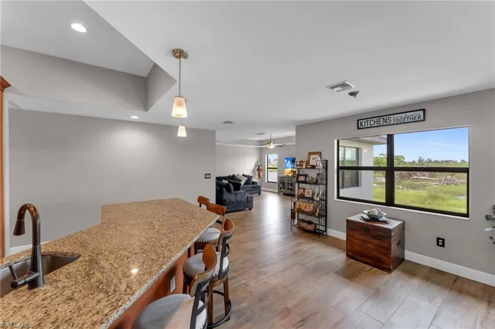Kitchen featuring a kitchen breakfast bar, hanging light fixtures, light wood finished floors, open floor plan, and a ceiling fan