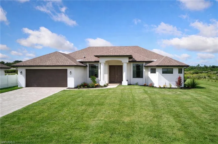 View of front of property featuring stucco siding, a shingled roof, a front lawn, and driveway