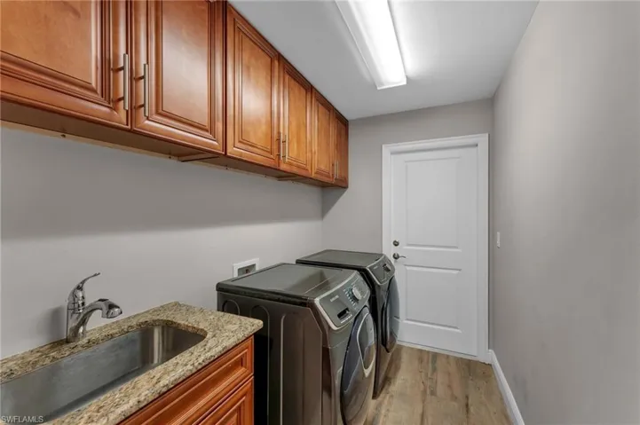Laundry area with light wood-style floors, washer and clothes dryer, and cabinet space