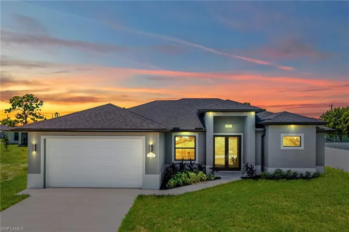 Prairie-style home with an attached garage, a front lawn, concrete driveway, stucco siding, and roof with shingles