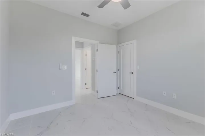 Unfurnished bedroom featuring light marble finish flooring and ceiling fan