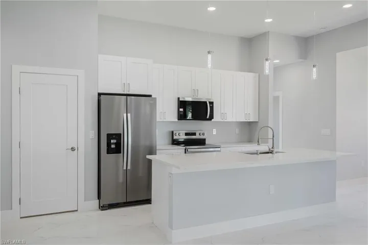 Kitchen featuring stainless steel appliances, light marble finish flooring, and white cabinets