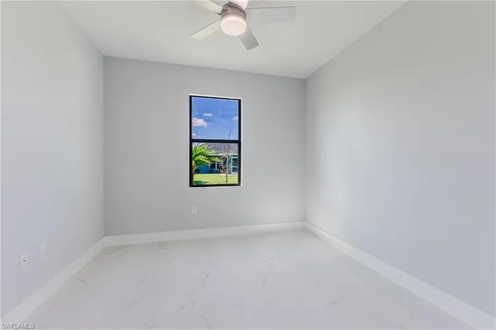 Unfurnished room featuring light marble finish flooring and ceiling fan
