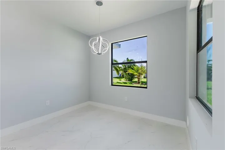 Unfurnished room with light marble finish flooring and a chandelier