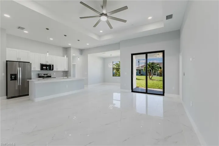 Unfurnished living room with a ceiling fan, recessed lighting, and a raised ceiling