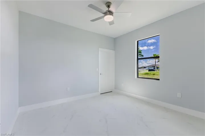 Unfurnished room featuring light marble finish flooring and ceiling fan
