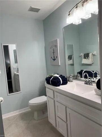 Bathroom vanity with white shaker-style cabinetry and a single integrated sink