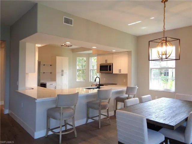 Kitchen with a kitchen breakfast bar, white cabinetry, a peninsula, and stainless steel microwave