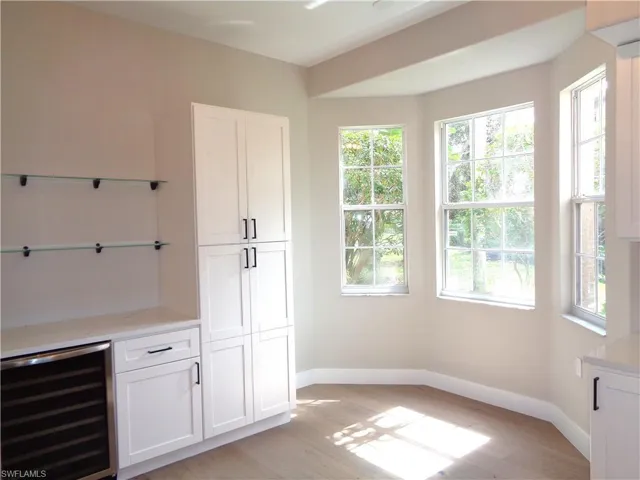 Bar area with wine cooler, white cabinetry, and light wood-style floors
