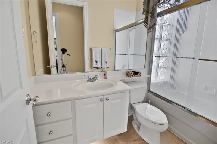 Full guest bathroom featuring vanity and shower / bath combination with glass door