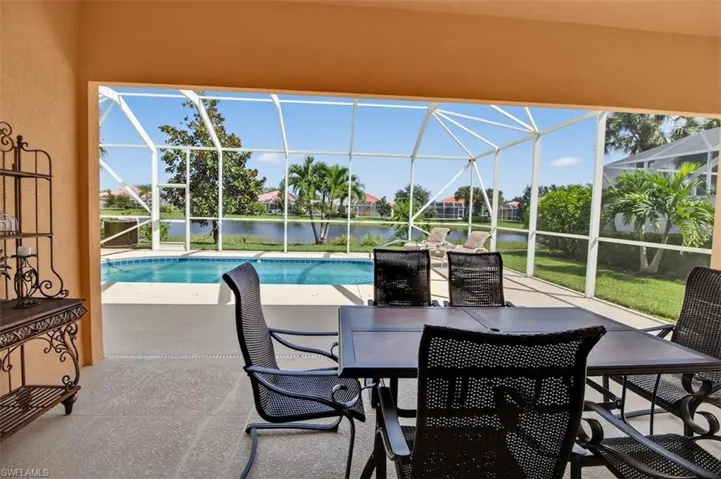 View of patio featuring a sunroom, an outdoor pool, a water view, and glass enclosure