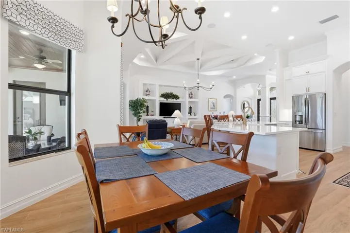 Dining area featuring light wood-type flooring, arched walkways, recessed lighting, a chandelier, and coffered ceiling