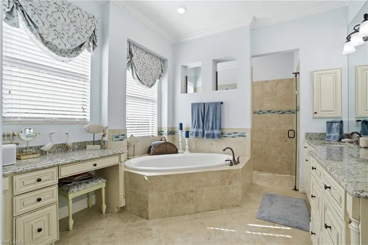 Bathroom with a garden tub, vanity, a shower stall, crown molding, and light tile patterned floors