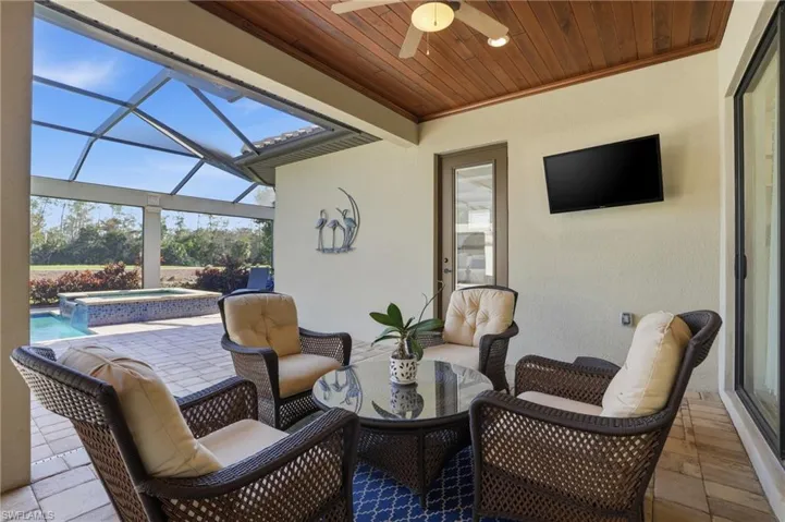 View of patio with a lanai, ceiling fan, a sunroom, and a pool with connected hot tub