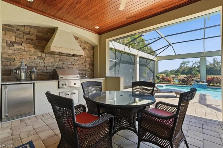 View of patio / terrace featuring outdoor dining space, an outdoor kitchen, a sunroom, a lanai, and an outdoor pool
