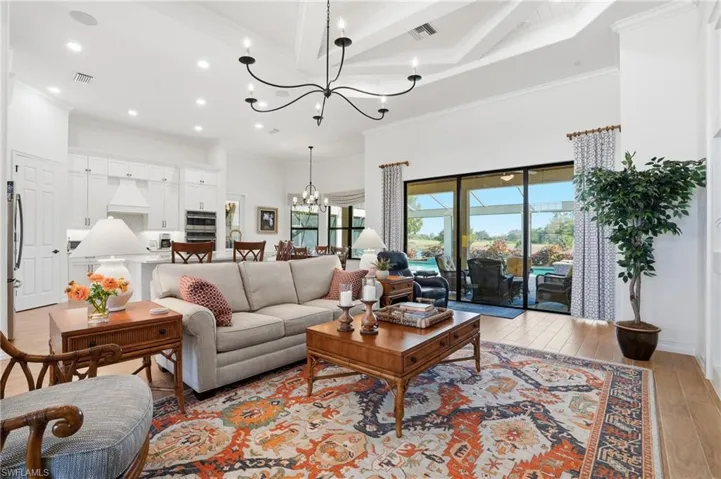Living room with light wood finished floors, crown molding, recessed lighting, beamed ceiling, and coffered ceiling