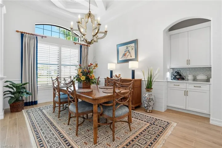 Dining room featuring ornamental molding, light wood finished floors, a chandelier, coffered ceiling, and beamed ceiling