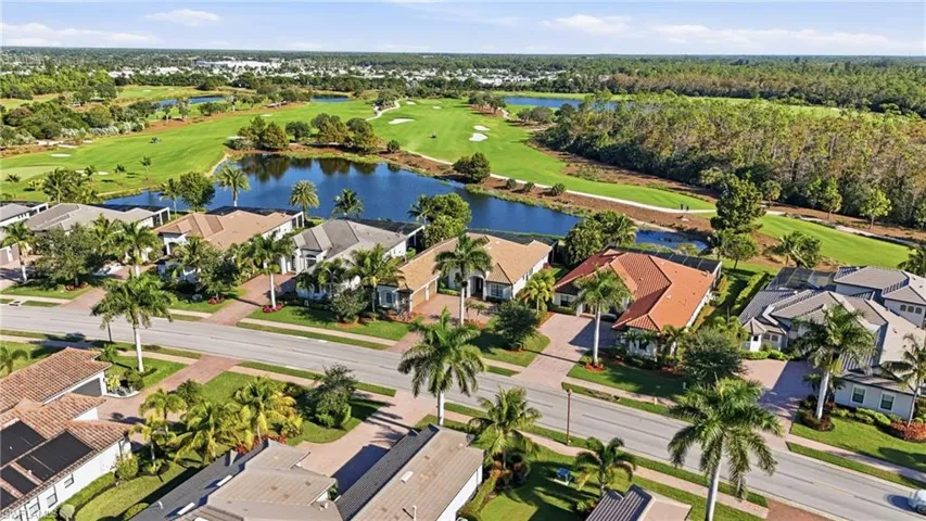 Aerial perspective of suburban area featuring a golf club and a nearby body of water