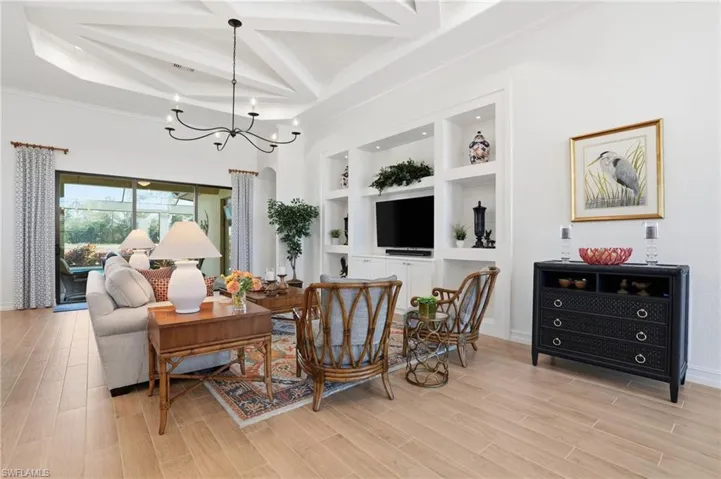 Living area with built in shelves, wood tiled floors, beamed ceiling, coffered ceiling, and a chandelier