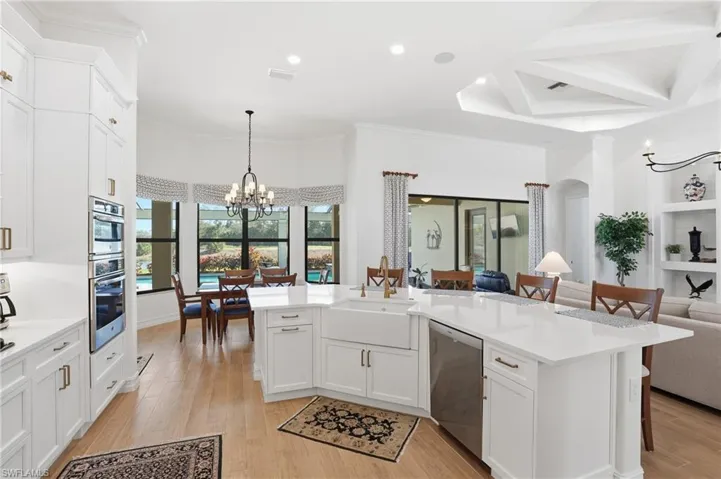 Kitchen with a breakfast bar area, white cabinets, a chandelier, open floor plan, and stainless steel dishwasher