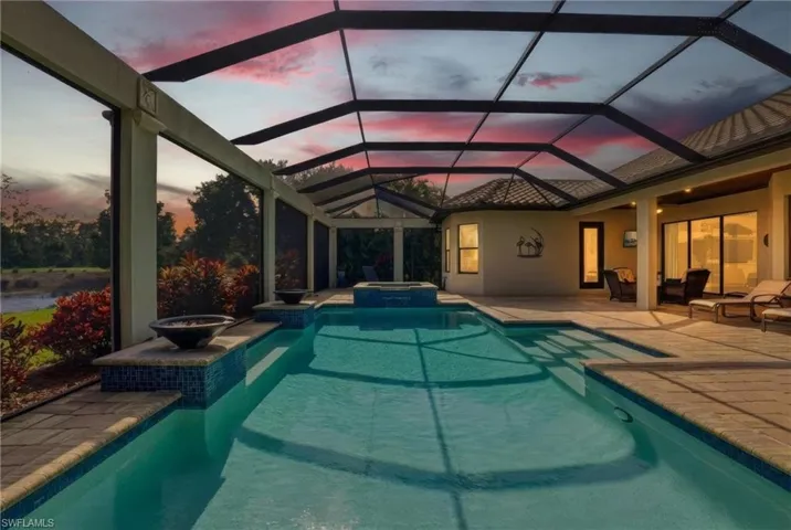 View of pool featuring a patio, a sunroom, a pool with connected hot tub, and a lanai