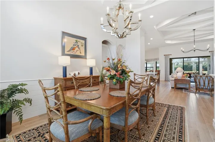 Dining area featuring a chandelier, light wood-style floors, arched walkways, beamed ceiling, and recessed lighting